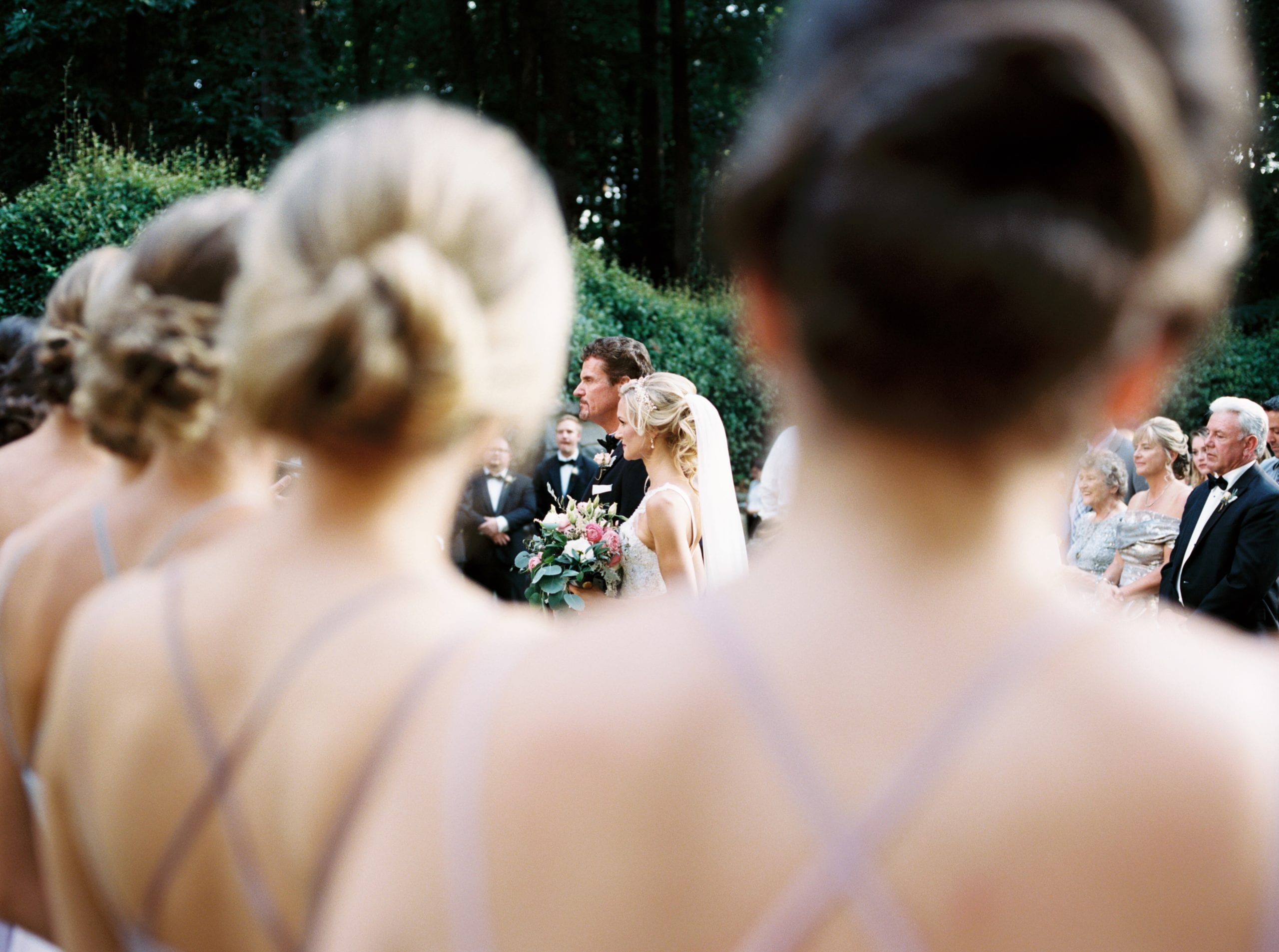 A bridesmaid's view of a swan house wedding ceremony held in the historic gardens in front of the coach house.