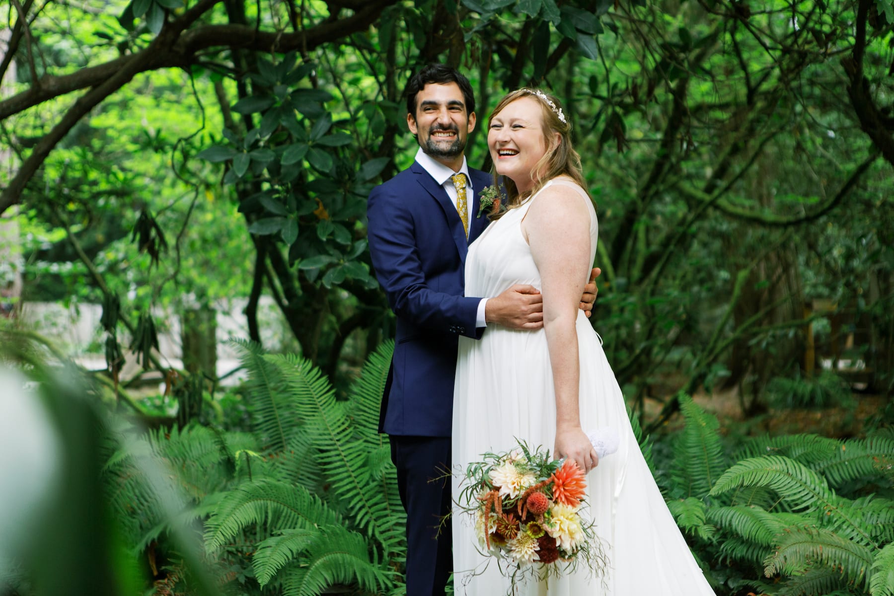 Couple laughs in fern filled forest at their Kiana Lodge wedding.